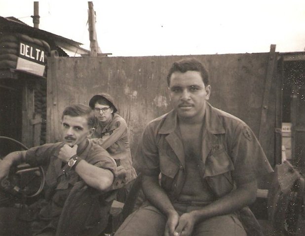 Jackie Lewis (hat on), Ernesto Roque(sitting on back of jeep), driver unknown